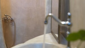 Een badkamer met een wastafel, douche en spiegel.