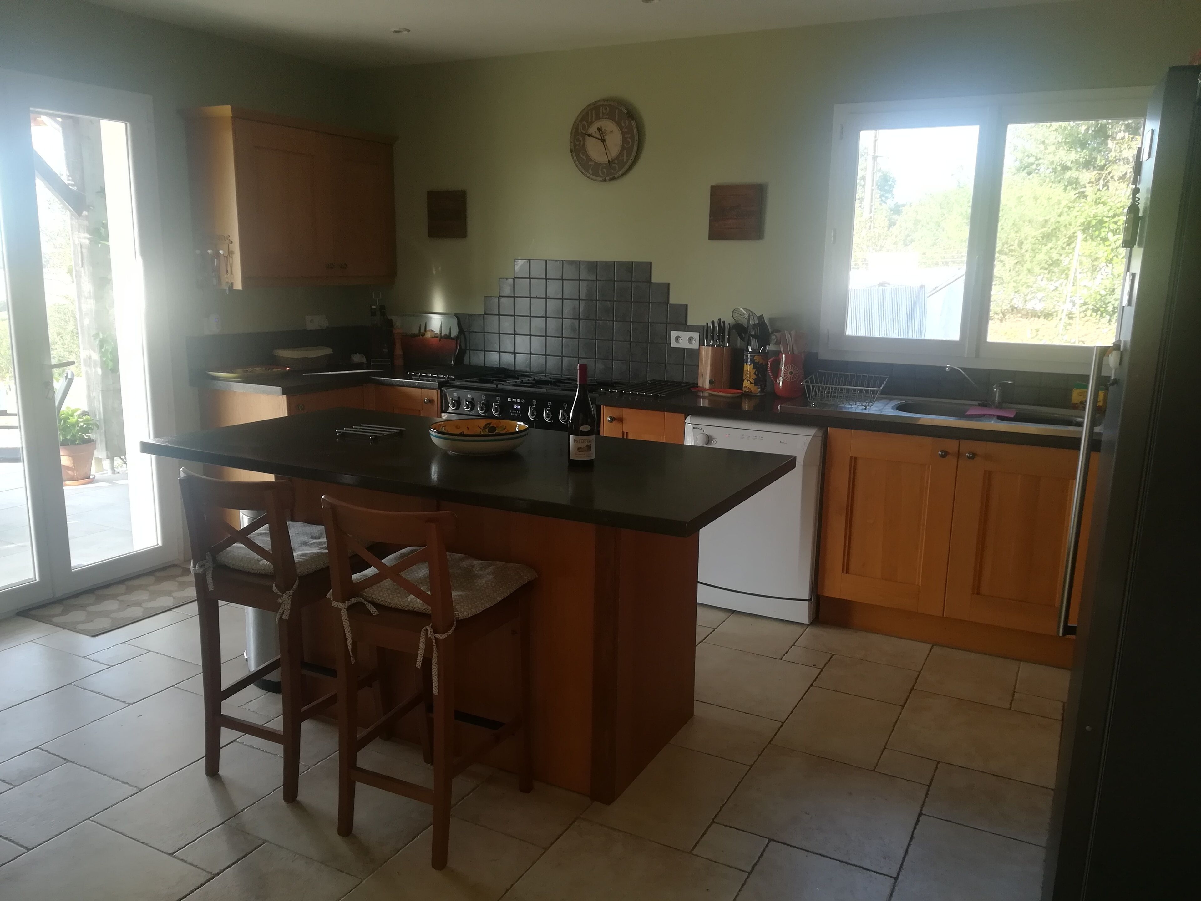 A kitchen with a central island, wooden cabinets, a stove, and a dishwasher.