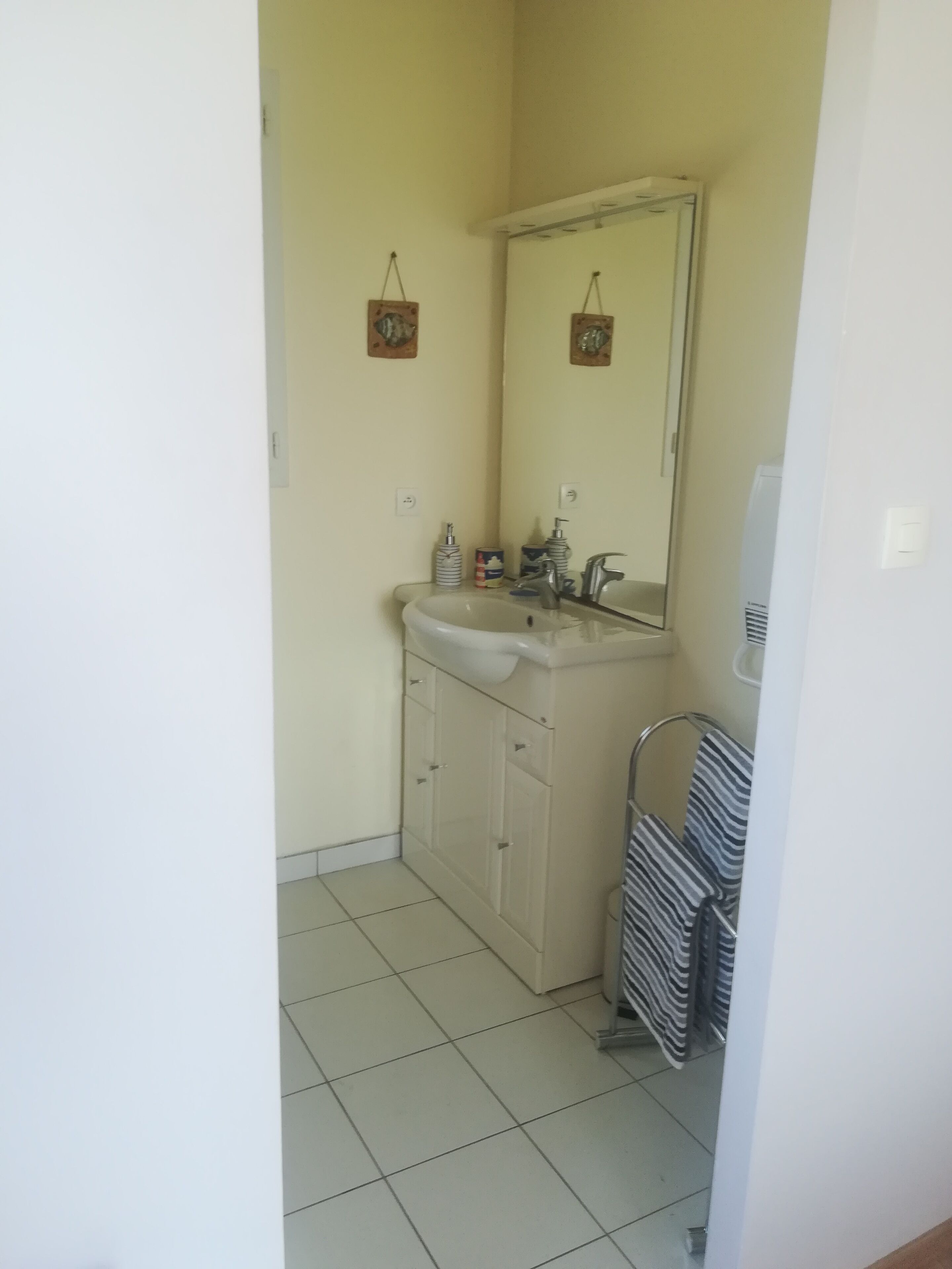 Un baño pequeño con lavamanos, espejo y piso de baldosas.