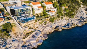 A coastal property with modern architecture, including a glass-roofed building and a stone staircase leading to a pool.