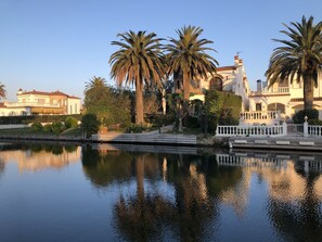 A waterfront property with a reflective pool, palm trees, and Mediterranean-style architecture. - Spanish waterfront villa with tower in Empuriabrava with pool, air conditioning (Empuriabrava)
