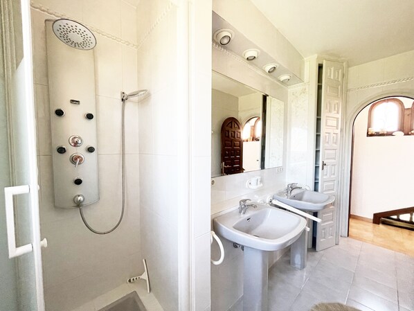 A bathroom with a shower, two sinks, a mirror, and a door leading to another room. - Spanish waterfront villa with tower in Empuriabrava with pool, air conditioning (Empuriabrava)