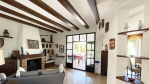 Uma sala de estar ampla com lareira, um sofá e um espaço de jantar com mesa e cadeiras.