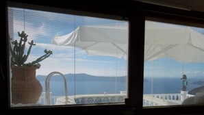 Une fenêtre donnant sur une zone côtière, avec vue sur un pont et un phare.