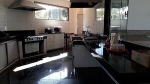 Una cucina moderna con mobili bianchi, un piano di lavoro nero, elettrodomestici in acciaio inossidabile e una finestra che lascia entrare luce naturale.