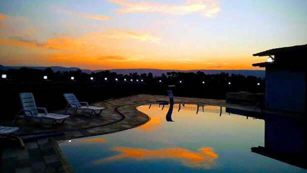 Piscina al crepuscolo con sedie a sdraio e vista sul tramonto.
