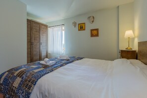 A hotel room with a large bed, a wooden wardrobe, a window with curtains, and a bedside table with a lamp. - Stone House Nera with Private Pool (Dračevac)
