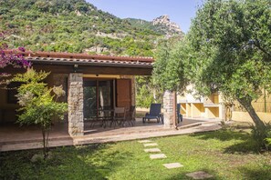 A stone building with a tiled roof, outdoor seating, and a view of a mountainous landscape. - Su Moddissi by All4sardinia (Cardedu)