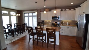 A kitchen with wooden cabinets, a stainless steel refrigerator, and a dining area with dark wooden chairs and a table.