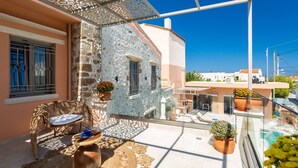 Ein Balkon mit Korbstuhl, kleinem Tisch und Topfpflanzen.