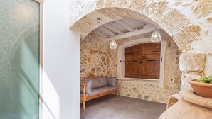 Ein Zimmer mit Stehwänden, einer Holzbänkl und einem großen Fenster, mit einem Blumentopf.