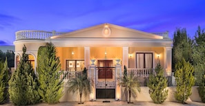 A grand building with a symmetrical facade, a central entrance with a decorative gate, and a balcony with a railing.