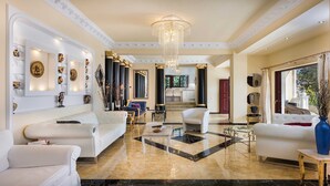 Un salón espacioso con candelabro, sofás blancos y suelo de mármol.