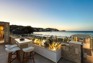 A terrace with a view of the sea, featuring a bar area with stools and a built-in planter with plants. - Villa Moana - Beachfront Coastal Dreams by etouri (Rethymno)