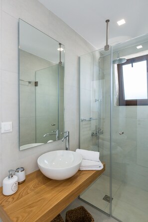 A modern bathroom with a glass shower enclosure, a large mirror, a wooden vanity, and a white sink. - Villa Moana - Beachfront Coastal Dreams by etouri (Rethymno)