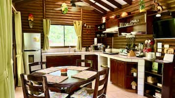 Een landelijke keuken met houten kastjes, een eettafel met stoelen en een inbouwoven.
