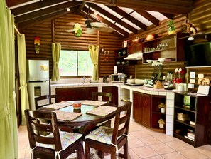 A rustic kitchen with wooden cabinets, a dining table with chairs, and a built-in oven.