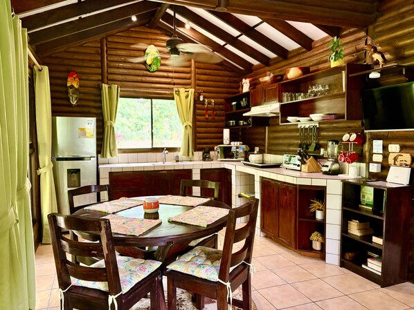 Une cuisine rustique avec des meubles de rangement en bois, une table à manger avec des chaises et un four encastré.