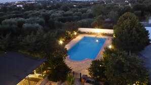 Ein rechteckiger Pool, umgeben von einer Steindeckfläche, mit einem Zaun und Bäumen im Hintergrund.