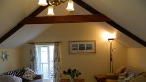 Un accogliente soggiorno con soffitto in legno, due divani, un tavolino e una lampada da terra.