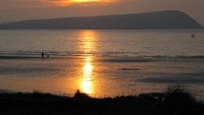 Un tramonto sul mare calmo, con la silhouette di una collina sullo sfondo.