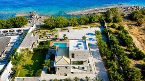 A resort with a swimming pool, a covered outdoor area, and a view of the sea.