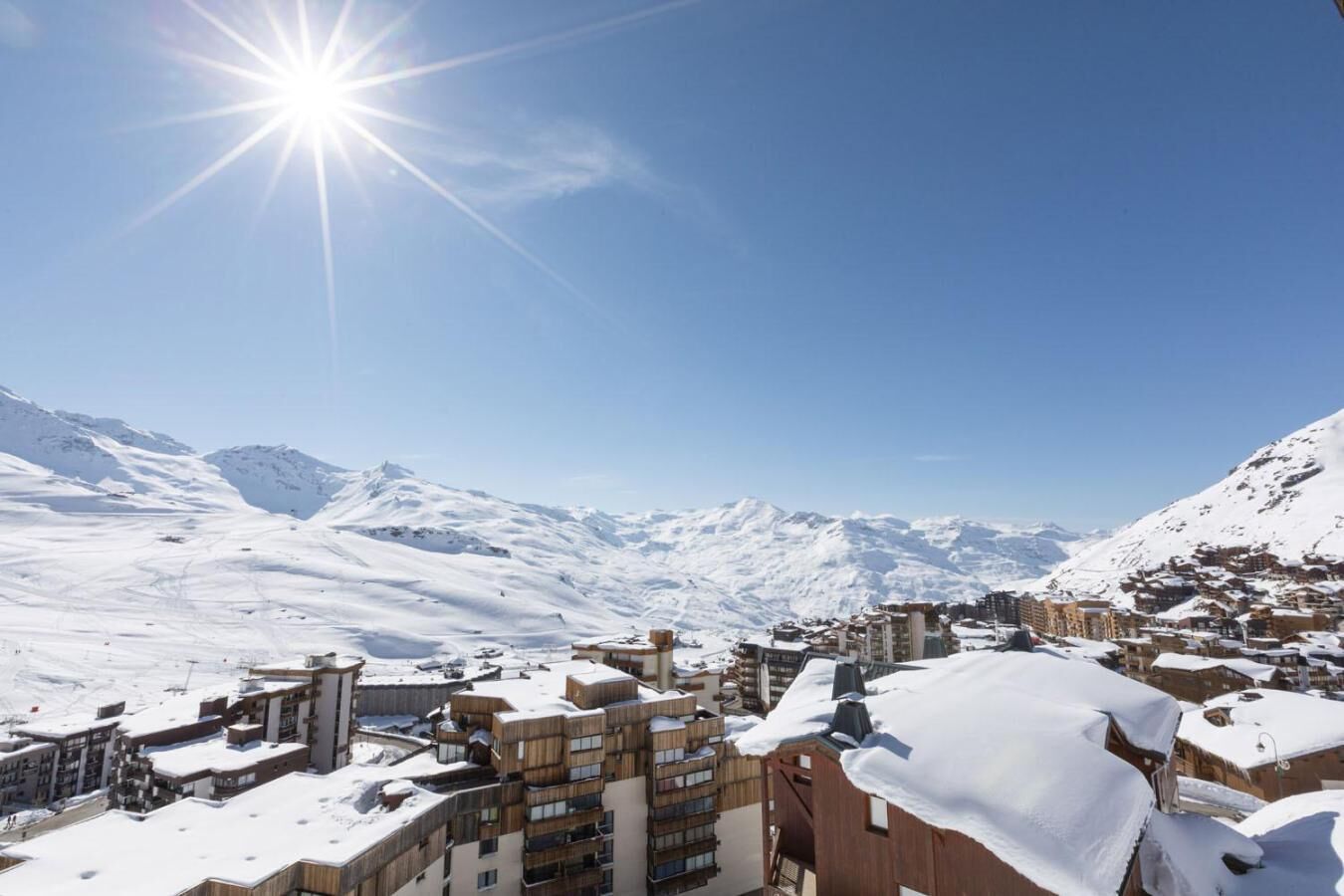 Une ville de montagne enneigée, avec des bâtiments modernes et un ciel dégagé.