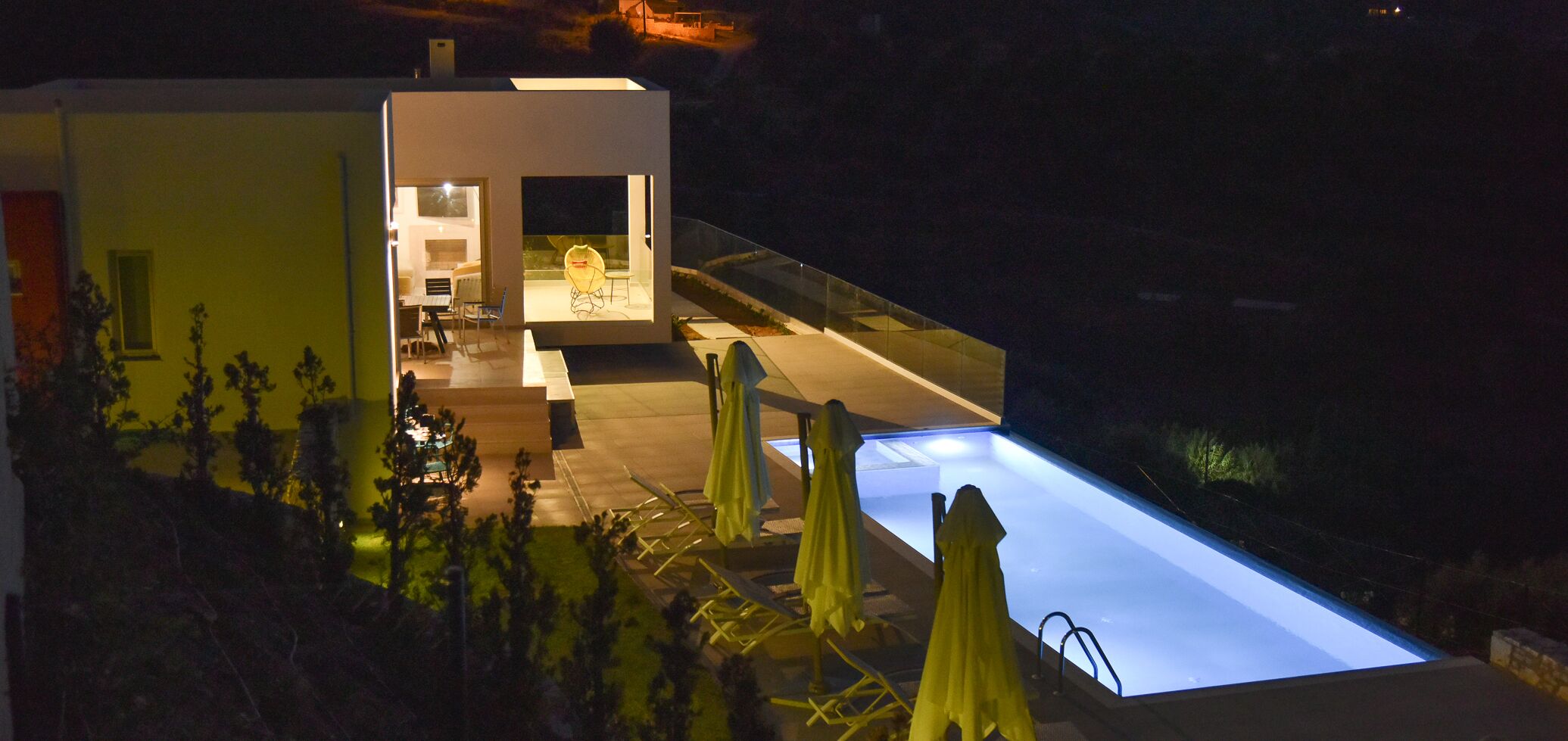 Una casa moderna con piscina, mobiliario exterior y un interior bien iluminado.