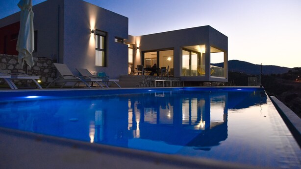 Ein modernes Haus mit Schwimmbad, Sitzgelegenheiten im Freien und Bergblick.