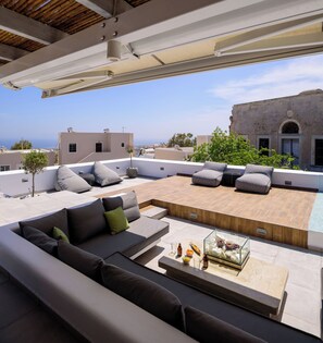 A rooftop terrace with a modern outdoor seating area, a pool, and a view of the cityscape.