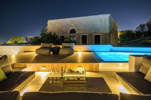 Zona de piscina en la azotea con mobiliario y vistas a un edificio.