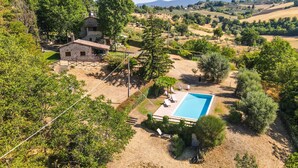 Una villa con piscina, rodeada de exuberante vegetación y colinas.