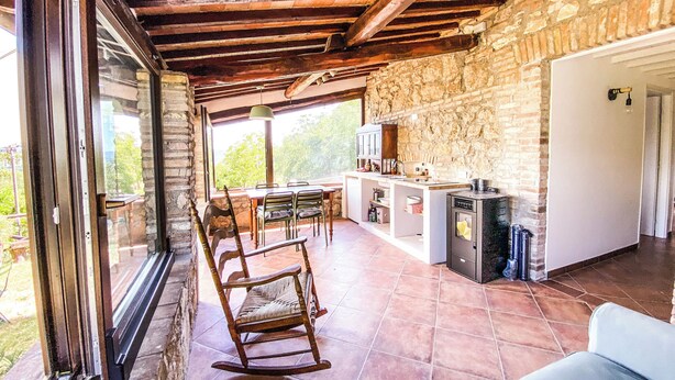 Una cocina rústica con paredes de piedra, techo de madera y un comedor con una mecedora y una mesa.