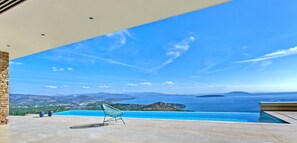 An infinity pool with a clear view of the sea and distant mountains.
