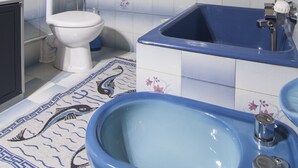 A bathroom with a toilet, a blue bathtub, and a sink. - Cosi Apartment in village (Lakka Paxos)