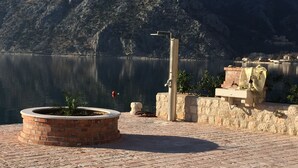 A waterfront patio with a brick planter, a water fountain, and a stone wall. - Exotic,sunny and peacfull (Dobrota)