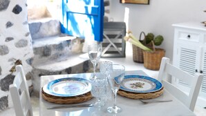 Een eettafel met twee borden, twee wijnglazen en een mand met groenten.