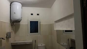 Een bad/douchecombinatie, een bidet, handdoeken, zeep