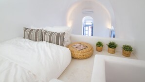 Een slaapkamer met een bed, een bank en een klein balkon met plantenpotten.