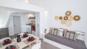 Een moderne, compacte leefruimte met een eethoek, kitchenette en een gezellige zithoek met een bank en decoratieve wanddecoraties.