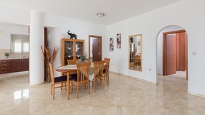 Un'ampia sala da pranzo con un tavolo e sedie in legno, un mobiletto con ante in vetro e un grande specchio appeso alla parete.