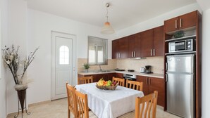 Una cucina moderna con mobili in legno, un frigorifero in acciaio inossidabile, un forno a microonde e un tavolo da pranzo con una ciotola di frutta.