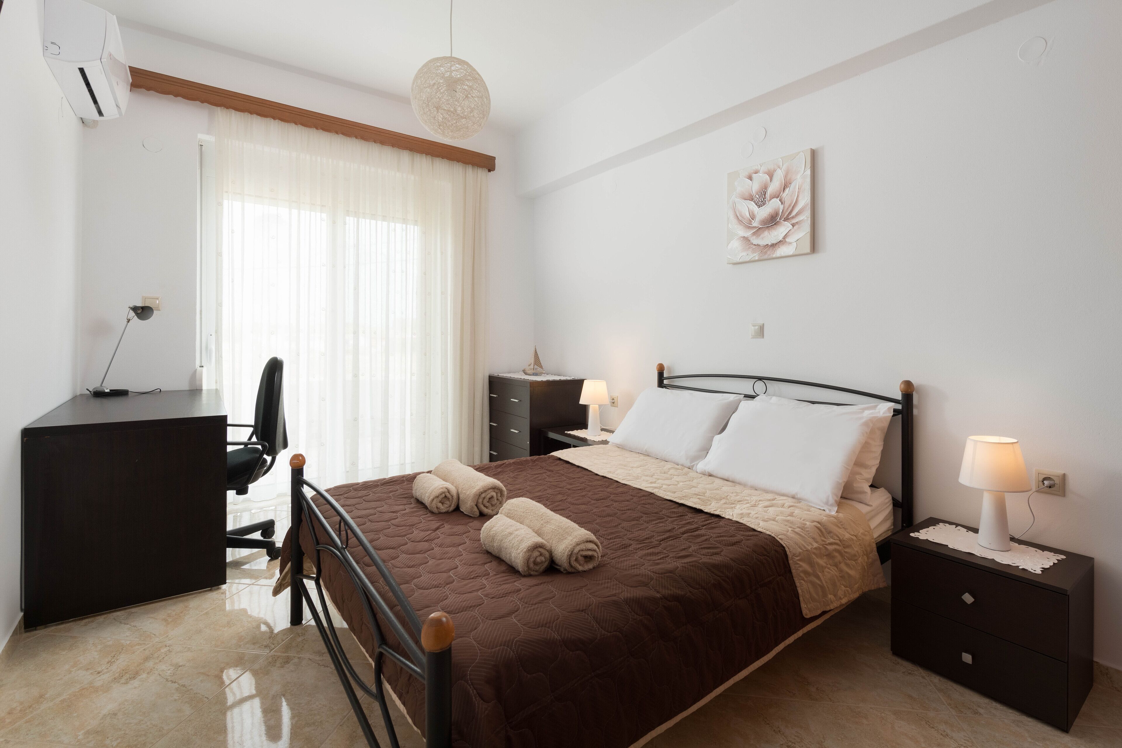 Ein Schlafzimmer mit einem Bett, Nachttischen, einem Schreibtisch und einem Stuhl.