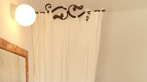 Une salle de bain avec un miroir encadré en bois, un lavabo blanc, une serviette, un bol en bois contenant des bougies et des toilettes.