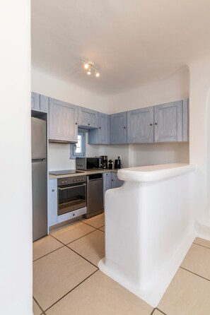 A modern kitchen with light blue cabinets, stainless steel appliances, and a white countertop.