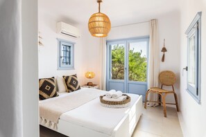 A bedroom with a bed, a bedside lamp, a chair, and a window with curtains.