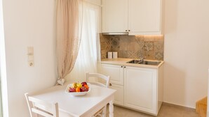 A small, clean kitchen with white cabinets, a sink, and a dining area with a table and chairs.