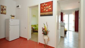 Une chambre d’hôtel avec un lit, une petite table, un réfrigérateur blanc et un tableau accroché au mur.