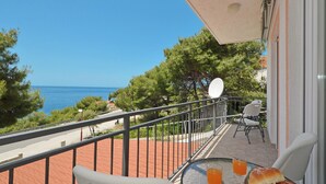 Un balcon avec une table, des chaises et une vue sur la mer.