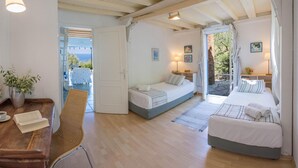 Une chambre confortable avec deux lits, un bureau en bois, une chaise et une vue sur la mer.